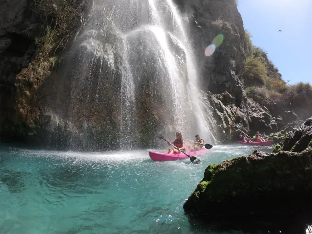 Pareja navegando en kayak bajo la cascada de Maro en Nerja Malaga con Wailele