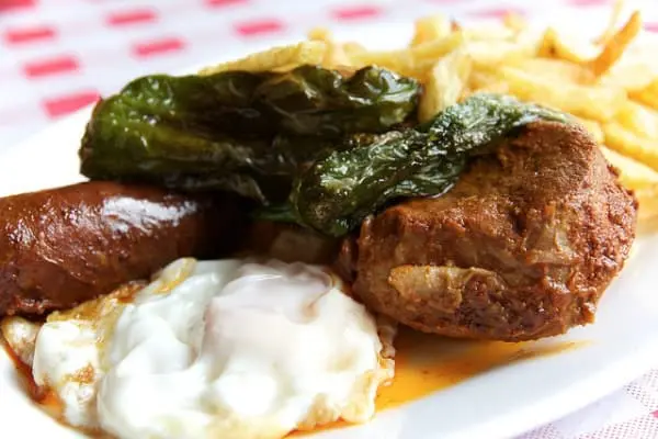 Plato de los montes de Malaga con huevo carne pimiento frito chorizo asado y patatas fritas