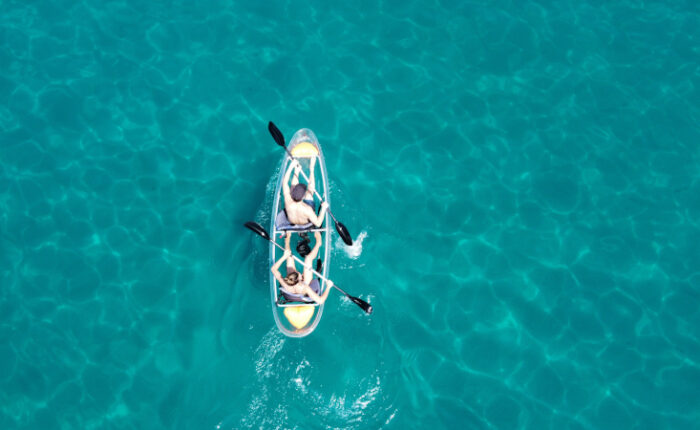 Vista de dron de una pareja navengando en un kayak transparente en aguas cristalinas de Burriana Maro Nerja