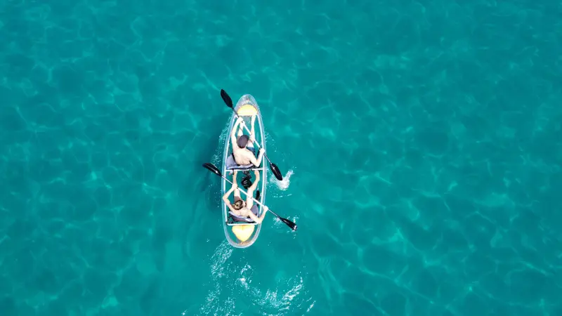 Vista de dron de una pareja navengando en un kayak transparente en aguas cristalinas de Burriana Maro Nerja