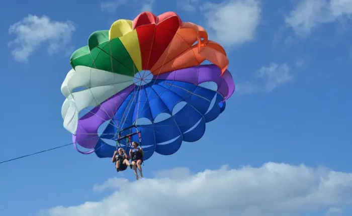 Hombre y Mujer practicando parasailing con un paracaidas multicolor en el mar